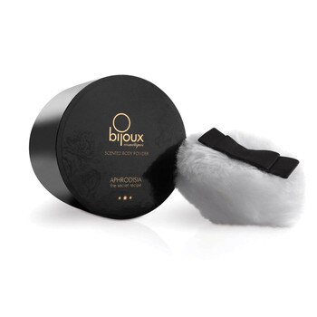 A round black container of Bijoux Aphrodisiac Kissable Body Powder on its side with a white application puff beside it.