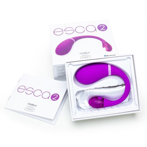 An image of the Esca 2 in its open packaging. The box is propped up against its lid, with the user manual to the left. Esca 2 is nestled in its tray on top of a satin privacy pouch.