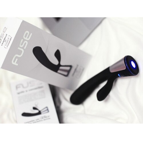A lifestyle image of Fuse in black with its packaging lying on white sheets with the LED illuminated.