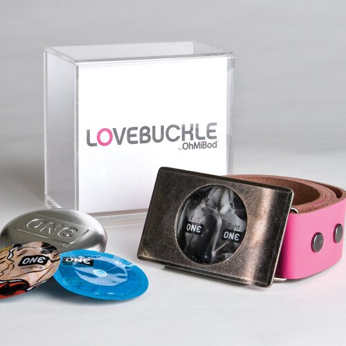 An image of the lovebuckle belt curled to the right, its box behind it, and several One condoms to the left.