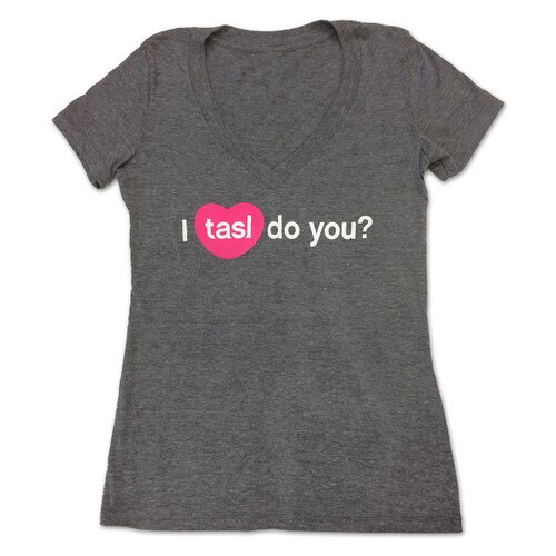 A dark gray V-neck t-shirt with the words "I tasl do you?" in white lettering with tasl inside a pink heart, recreating the icon for the tasl app.