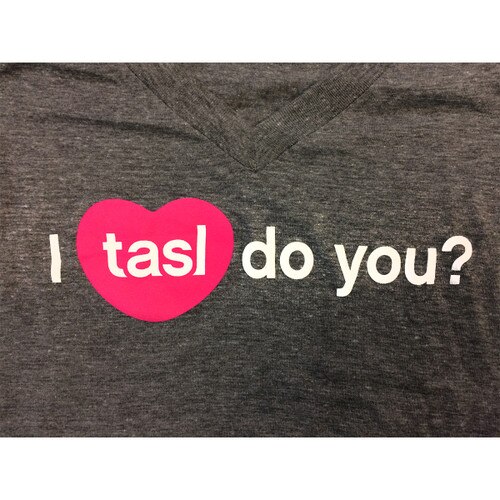 A close up image of "I tasl do you" on the dark gray t-shirt fabric.
