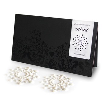 An image of a pair of pearl pasties arranged in a starburst shape next to their black and red packaging.