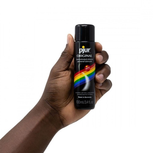 African American hand holding the Pjur Original Rainbow Edition 100ml bottle on a white background
