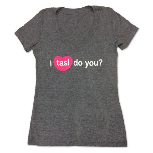 A dark gray V-neck t-shirt with the words "I tasl do you?" in white lettering with tasl inside a pink heart, recreating the icon for the tasl app.